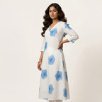Woman wearing a white dress with blue floral patterns on a light gray background