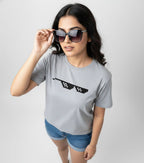 Woman wearing a gray t-shirt with a black graphic design on a plain background